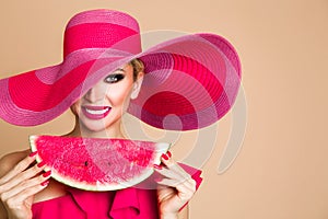 Beautiful female model with perfect face and red hat holding a watermelon at her face