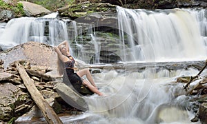 Beautiful female model posing in front of waterfall