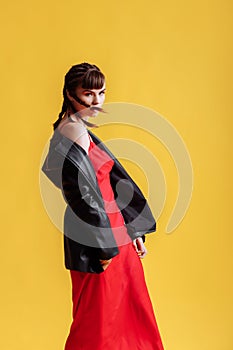 Beautiful female model in a red dress yellow background