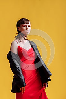 Beautiful female model in a red dress yellow background