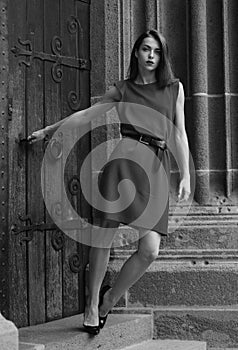 Beautiful female model in summer city in Europe. Trendy woman posing on the street background. Brunette with red dress.