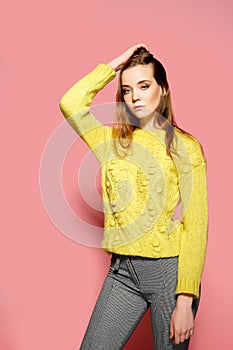 Beautiful female model wears casual comfrotable sweater, poses against pink background. Copyspace