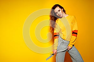 Beautiful female model wears casual comfrotable sweater, poses against yellow background. Copyspace