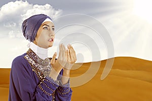Beautiful female muslim praying in blue at desert