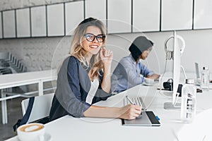 Beautiful female office worker carrying out administrative work for company. Indoor portrait of cute blonde student