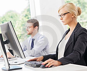 Beautiful female office worker in formalwear with colleague on background