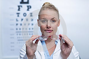 Beautiful female optometrist holding spectacles