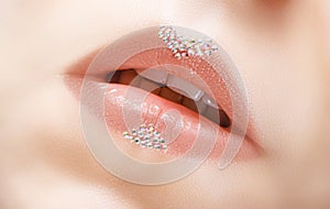 Beautiful female pink lips with glittering gems art decoration. Pink lipsgloss with bright jewel stones decor