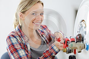 beautiful female plumber working on central heating boiler