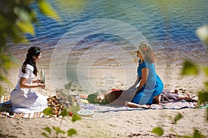 Beautiful female receiving energy sound massage with singing bowls and body massage on a river bank