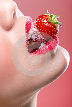 Beautiful female red lips, full with Granulated Sugar, biting a strawberry
