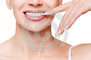 Beautiful female smile and mouth with healthy snowy even teeth. Woman touches her lips by finger, well groomed skin