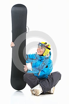 Beautiful female snowboarder sitting with snowboard in hands