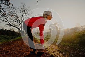 Beautiful female stretching hamstring before beginning exercise or run in the park during sunrise, dusk