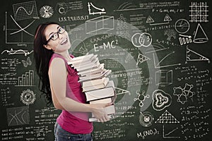 Beautiful female student bring stack of books in class photo