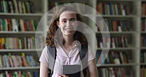 Beautiful female student stands in library showing thumbs up