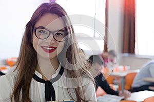 Beautiful female student wearing glasses standing at university campus interior