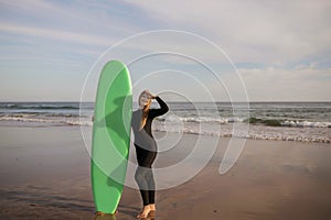 Beautiful Female Surfer Standing On The Beach And Holding Surf Board