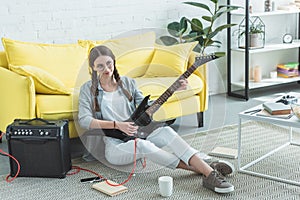 beautiful female teen guitarist playing electric guitar on floor