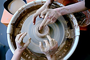 Beautiful female and teenage hands over the potter`s wheel. Sculpt from clay in a pottery workshop. Traditional pottery craft.