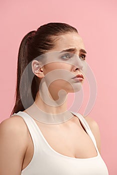 The young woman is looking sad on the pink background.