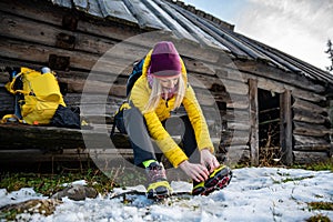 Beautiful female tourist in an alpine resort wears crampons before climbing the top.