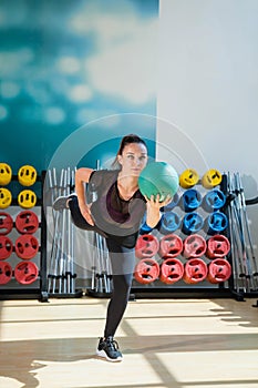 Beautiful female trainer shows exercises with a ball in the gym