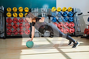 Beautiful female trainer shows exercises with a ball in the gym