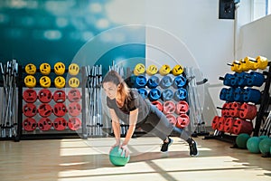 Beautiful female trainer shows exercises with a ball in the gym