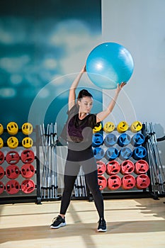 Beautiful female trainer shows exercises with a ball in the gym