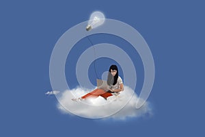 Beautiful female using laptop on cloud under lightbulb