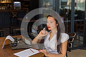 Female writer with vintage typewriter making notes in a coffee s