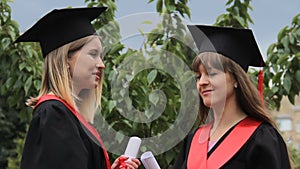 Beautiful females graduates discussing future plans after receiving diplomas