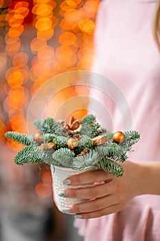 Beautiful festive arrangement of fresh spruce with ball toys in coffee Cup. Christmas mood. Bokeh of Garland lights on