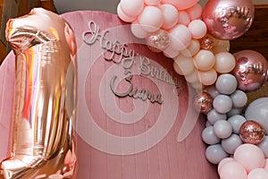 Beautiful festive decorations, pink and grey balloons arch and number one balloon on wooden round background. Little 1 year old