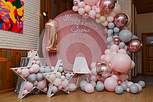 Beautiful festive decorations, pink and grey balloons arch, wooden stars, white chair and number one balloon on wooden round