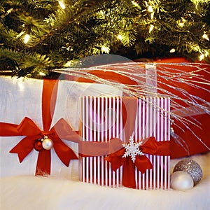 Beautiful, festive, fancy, wrapped Christmas gifts presents under lighted illuminated Christmas tree. Holidays at home