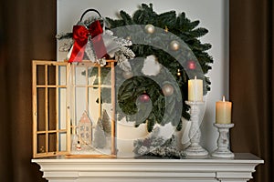 Beautiful festive lantern and candles on mantel near Christmas wreath