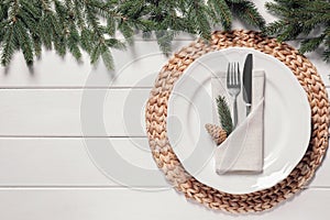 Beautiful festive place setting with cutlery and fir branches for Christmas dinner on white wooden table, flat lay. Space for text