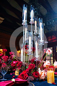 Beautiful festive table setting with fresh red flowers, napkins and candles.