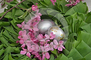 Beautiful festive wreath of green leaves with pink flowers and silver eggs. easter plants