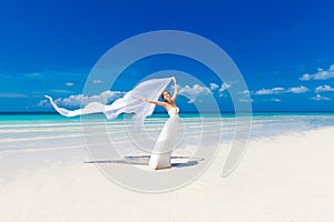 beautiful fiancee in white wedding dress and big long white train, stand on shore sea