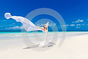 beautiful fiancee in white wedding dress and big long white train, stand on shore sea