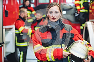 Beautiful fire fighter woman with her helmet standing in the firehouse photo