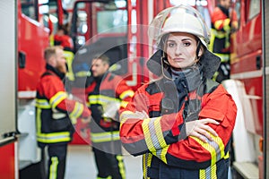 Beautiful fire fighter woman with her helmet standing in the firehouse