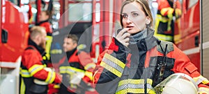 Beautiful fire fighter woman with her helmet standing in the firehouse