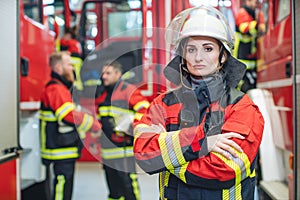 Beautiful fire fighter woman with her helmet standing in the firehouse photo