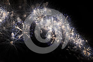 Multiple Fireworks in night sky in a composition in shades gold and white
