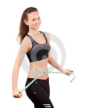 Beautiful fit girl measuring her waist with a green measuring tape in inch.