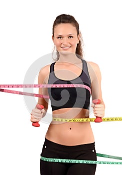 Beautiful fit girl with measuring tape around her bust, waist and hips holding dumbbells.